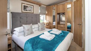 A bedroom with a large bed, a wooden wardrobe, and a nightstand. - 3-bed Lodge Sleeps 6 - Private Hot tub - Resort (St. Andrews)