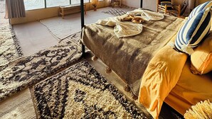 A spacious bedroom with a four-poster bed, large windows, and a view of the landscape. - Amskou Camp (Rissani)