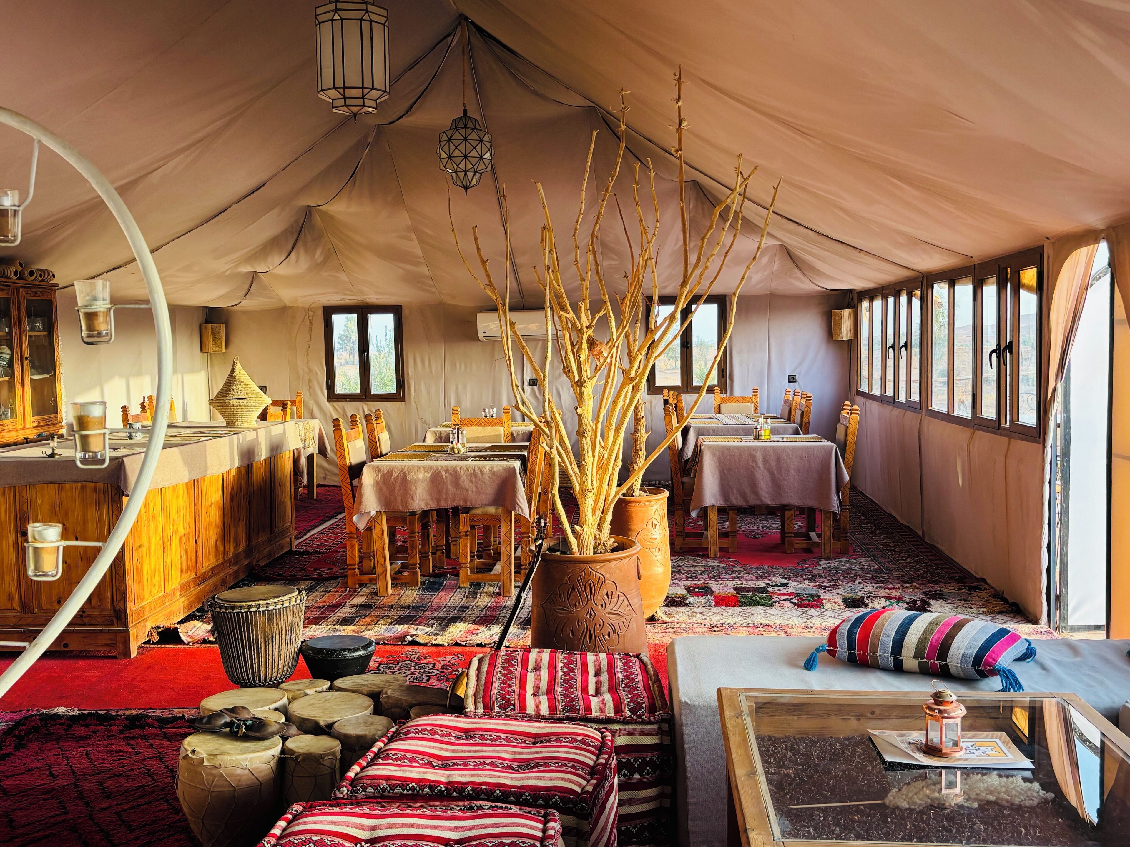 A tented accommodation with a dining area, tables, chairs, and a variety of decorative items.