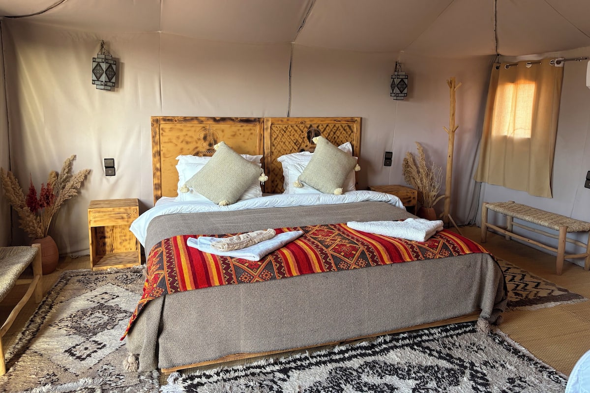 Un dormitorio amplio con una cama grande, cabecera de madera y un banco.