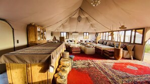 A tented accommodation with a large bed, multiple seating areas, and a red carpet. - Amskou Camp (Rissani)