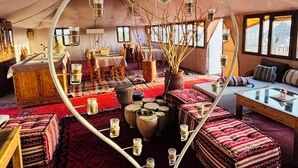 A tented room with a heart-shaped layout, featuring a dining area, seating, and a central decorative element. - Amskou Camp (Rissani)