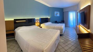 A hotel room with two beds, a desk, a chair, a TV, and a window with curtains.