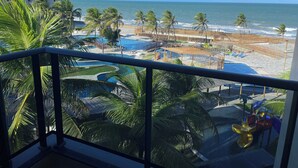 Une vue depuis un balcon donnant sur une piscine, une plage et l’océan.