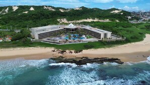 Un hôtel situé en bord de mer, doté d’une piscine centrale, de nombreuses chambres et offrant une vue sur l’océan.