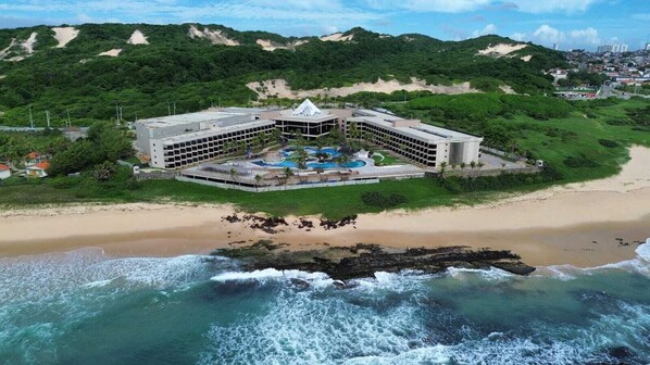 A beachfront hotel with a central pool, multiple guest rooms, and a view of the ocean. - Hotel Pirâmide Natal (Natal)