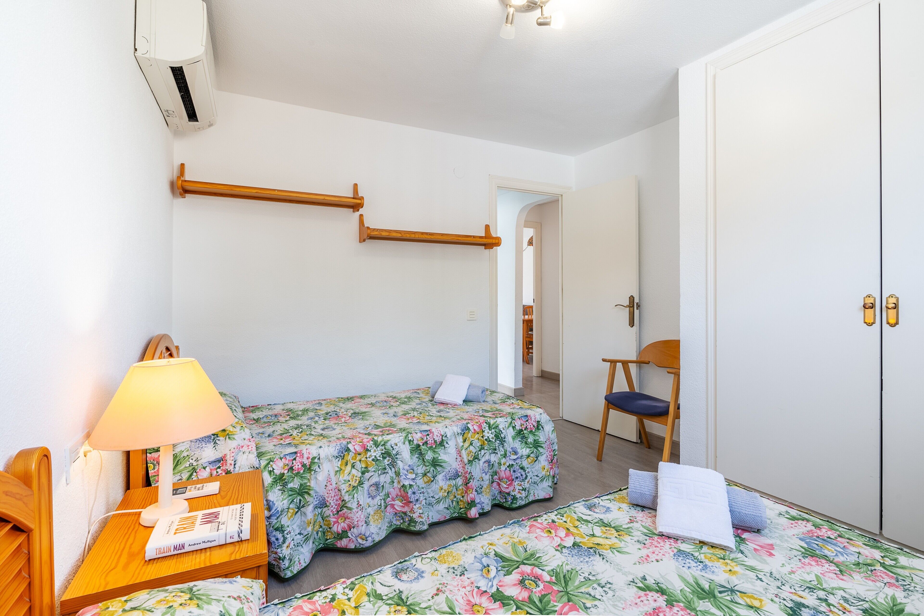 Una camera da letto con due letti, una poltrona, un comodino con una lampada e un armadio.