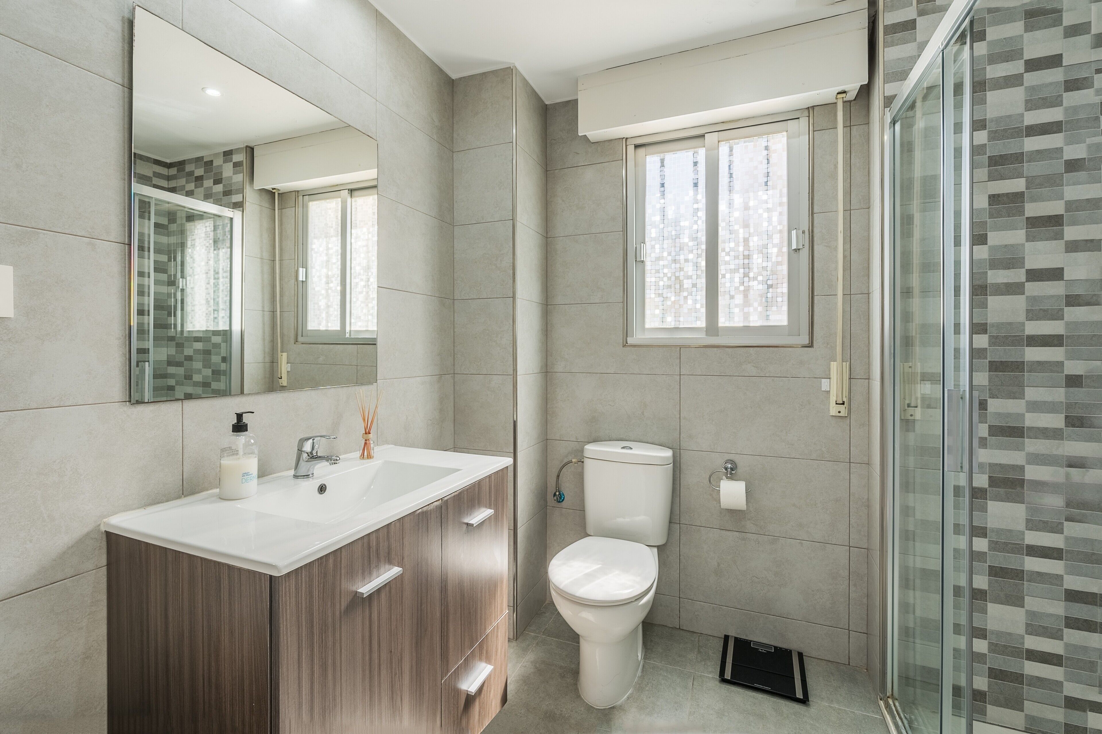 Een moderne badkamer met een grote spiegel, een wastafel, een toilet en een douche.