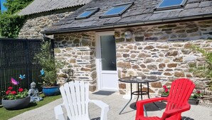A stone building with a door, a small table, and two chairs.