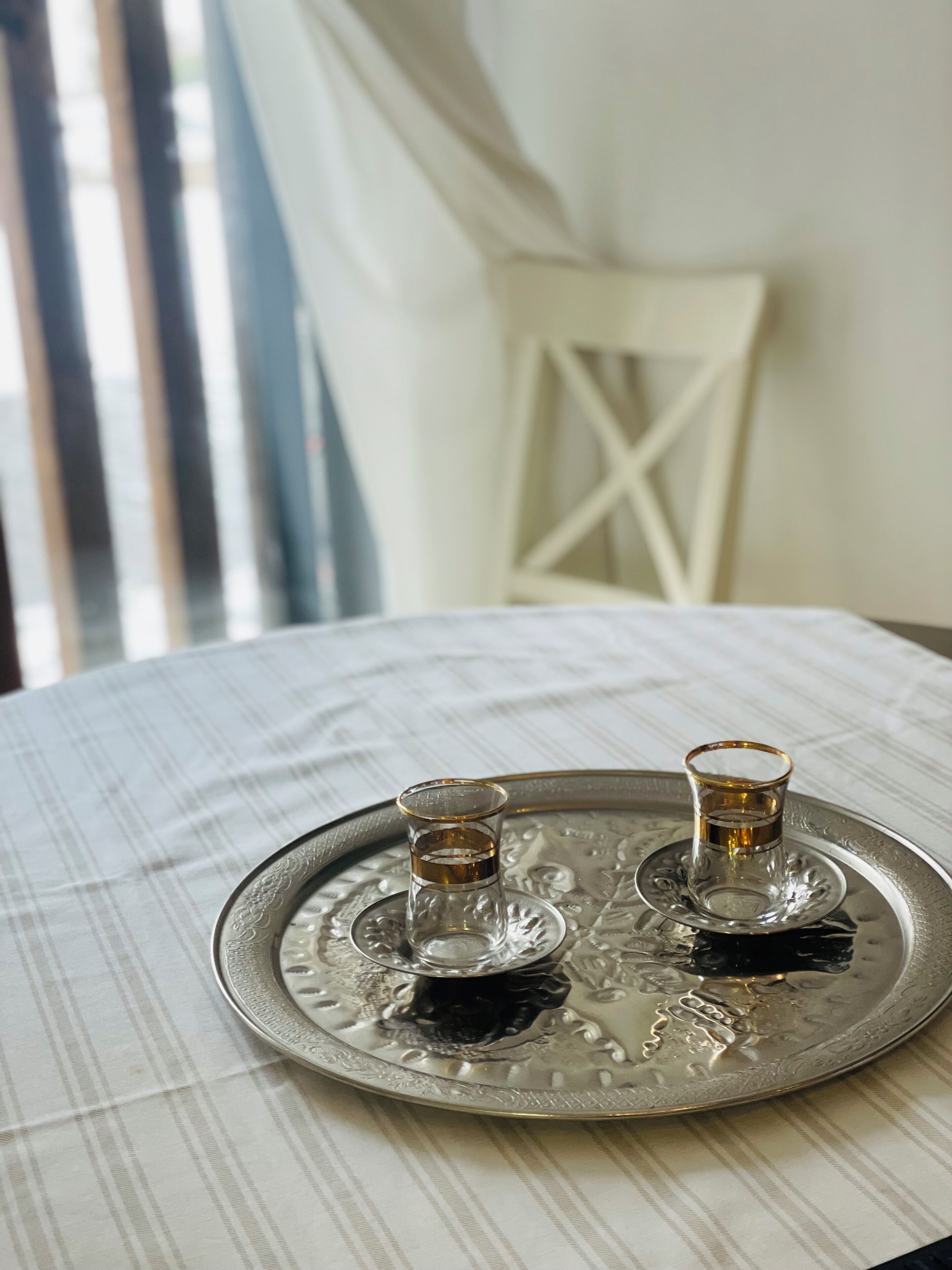 Una bandeja con dos vasos de un líquido oscuro, posiblemente vino, sobre una mesa con mantel a rayas.