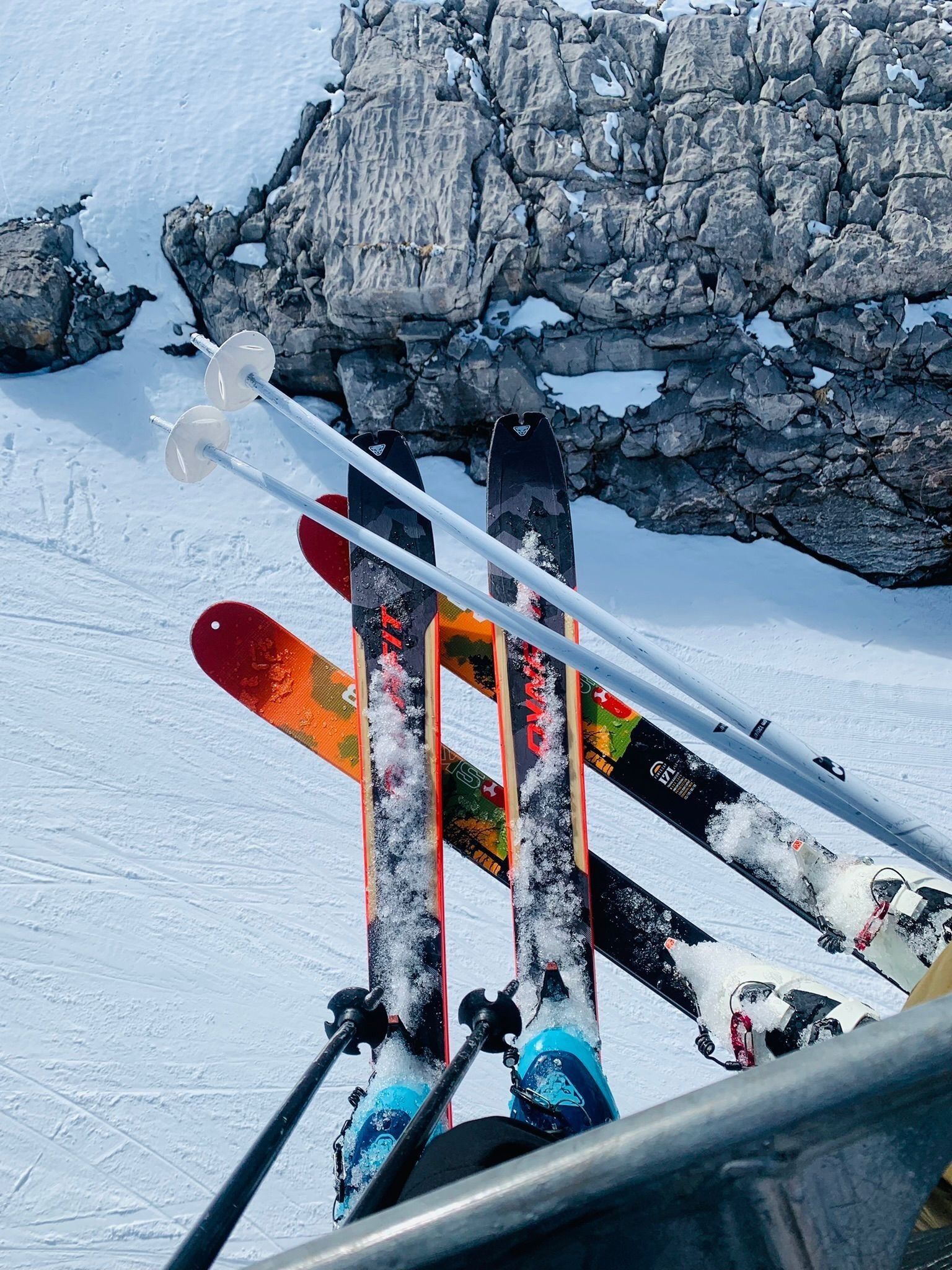 Un par de esquíes apoyados en una superficie rocosa con nieve.