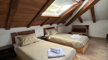 Una habitació amb dos llits de fusta, un fanal i un sostre de fusta.