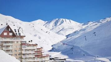 Une montagne enneigée, avec un télésiège et un bâtiment doté de balcons.