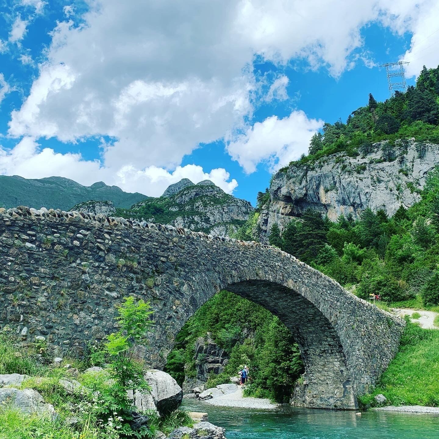 Un puente de piedra sobre un río, con montañas al fondo.