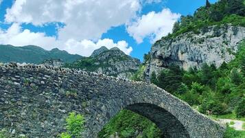 A stone bridge over a river with a mountainous backdrop.