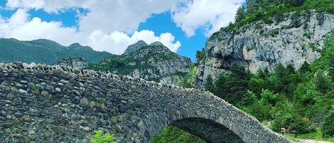 Un puente de piedra sobre un río, con montañas al fondo.