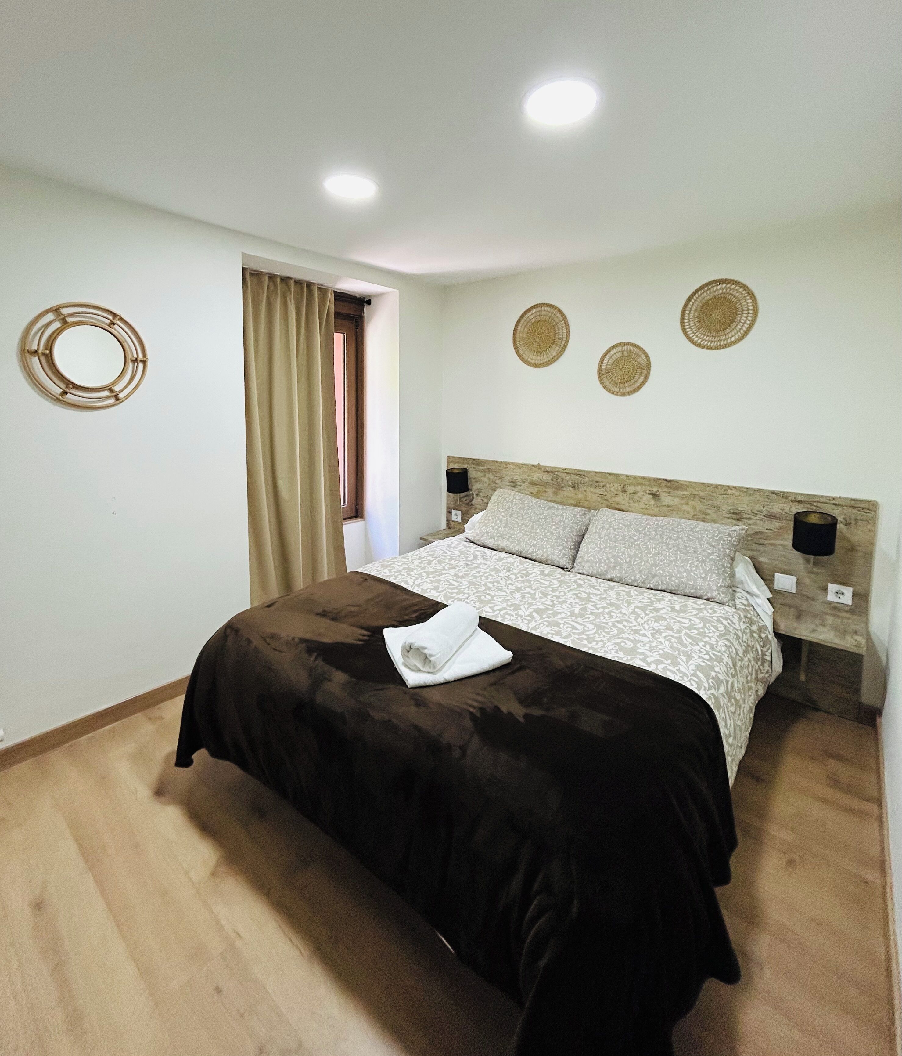 Een slaapkamer met een bed, een raam met gordijnen en wanddecoratie.