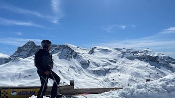 Une personne faisant du ski sur une montagne enneigée, avec une rampe en bois et un panneau portant le logo « ASTUN ».