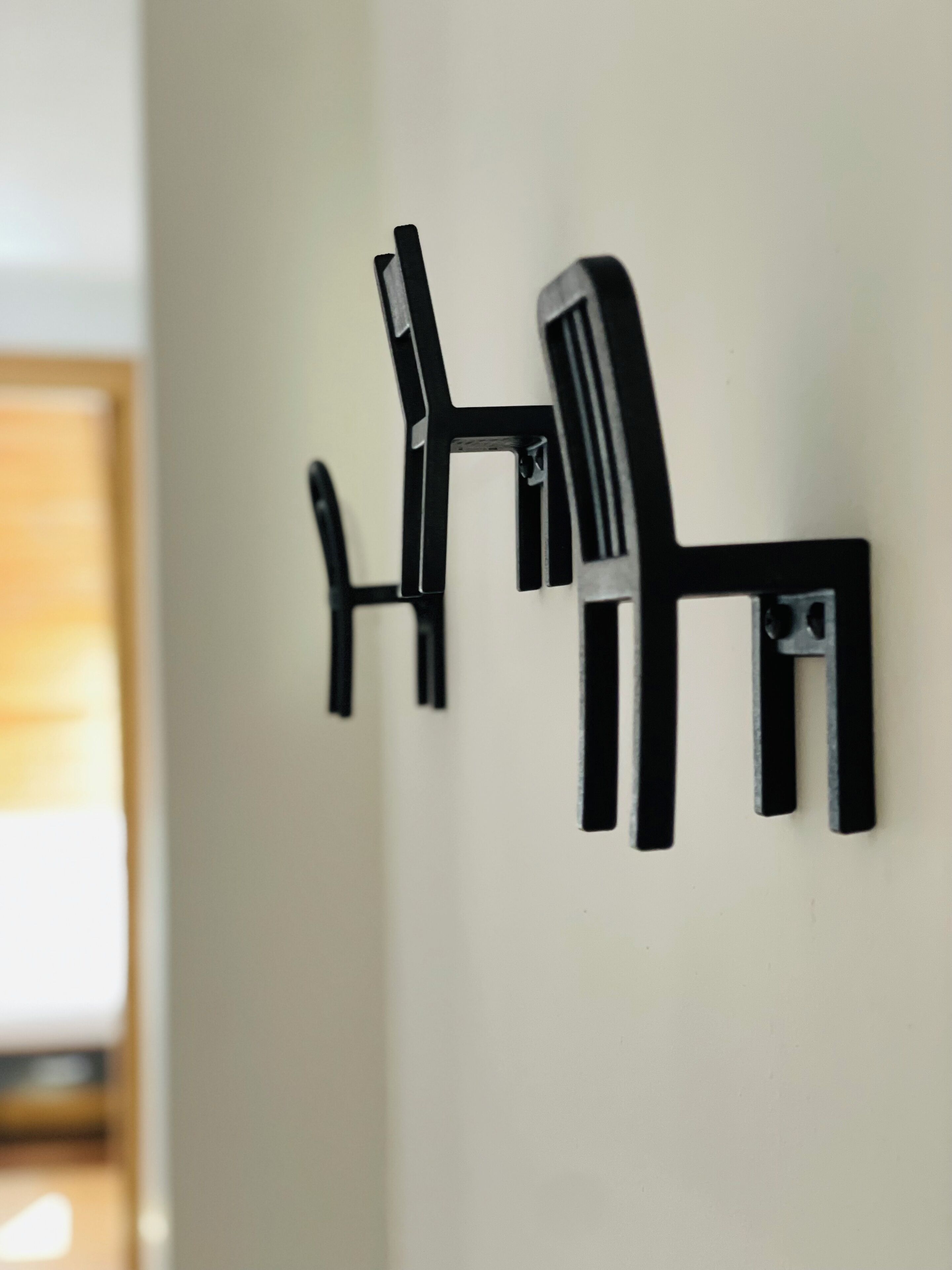 A wall-mounted black chair with a backrest and armrests.
