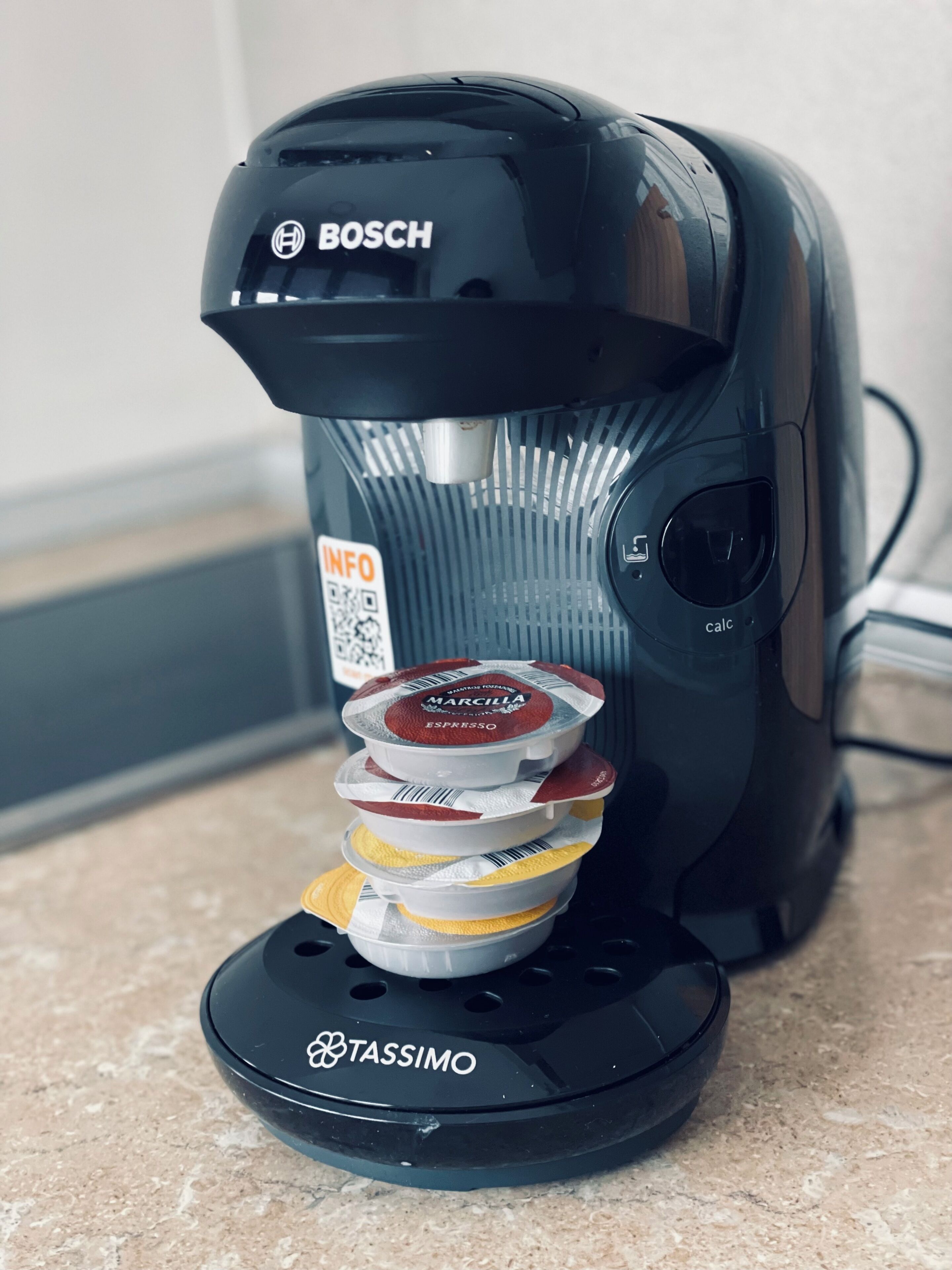 En kaffemaskine med en stabel kaffekapsler i bunden.