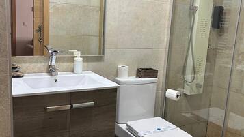 Un baño con lavabo, espejo, inodoro y ducha.