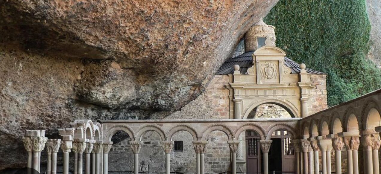 Un edificio histórico con fachada de piedra, un arco central y una serie de columnas.