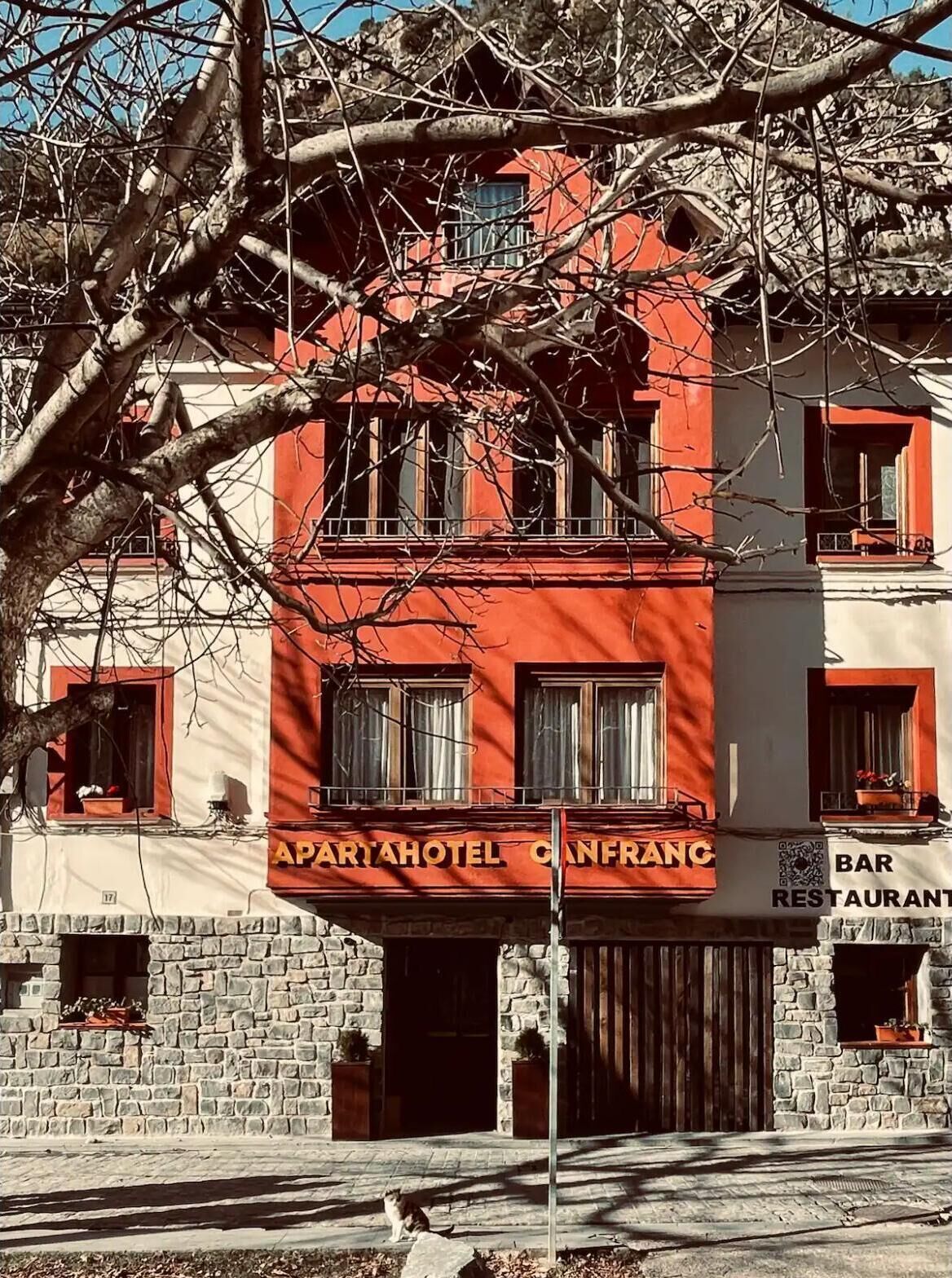 A two-story building with a red facade, balconies, and a stone base.
