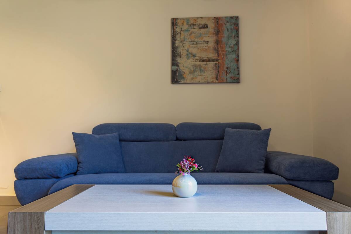A modern living room with a grey sofa, a white coffee table, and a vase with flowers.