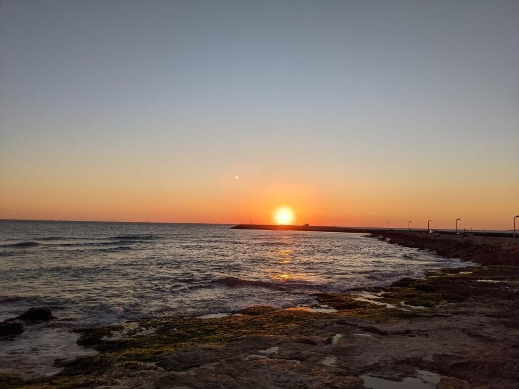 A sunset over a rocky shoreline with waves.