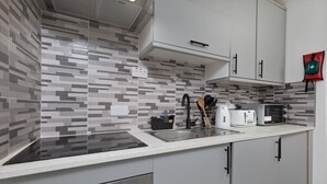 Una cocina moderna con armarios grises, un lavamanos de acero inoxidable y un microondas.