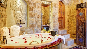 A stone-walled bathroom with a bathtub, towels, and a wooden cabinet. - Marbay Cave Cappadocia (Nevsehir)