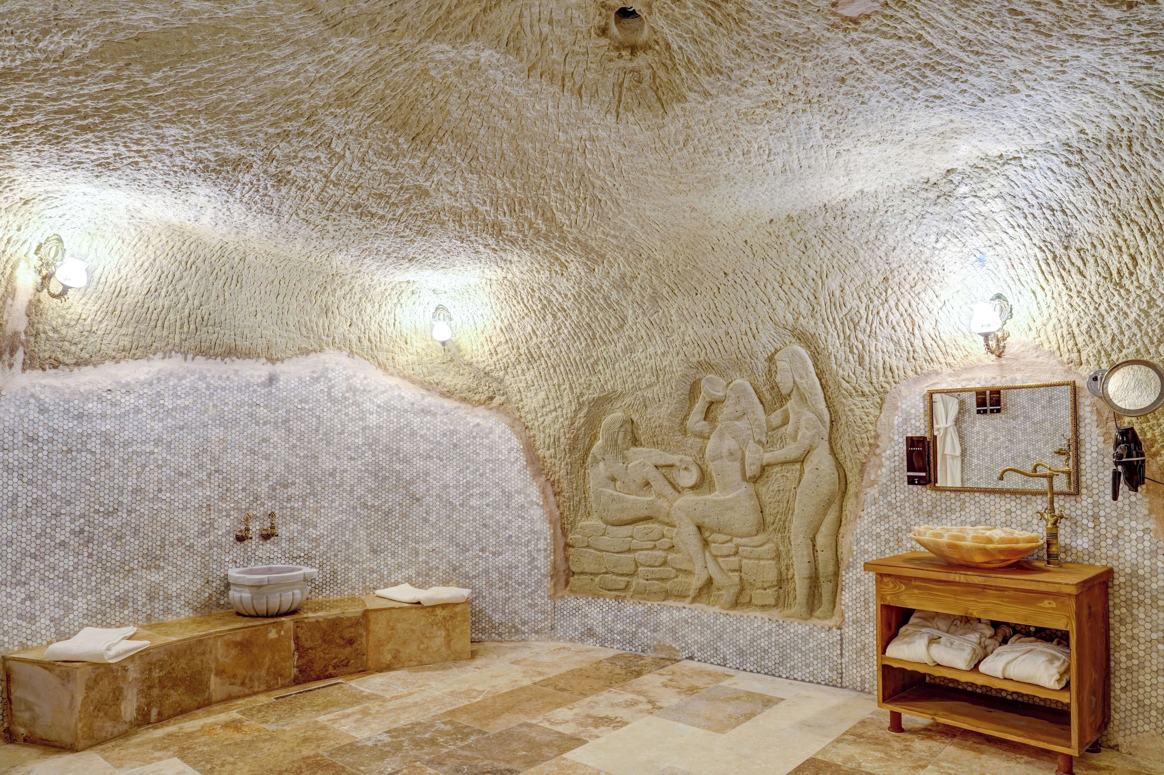 Un baño con techo texturizado, pared de piedra con relieves, tocador de madera y lavabo.