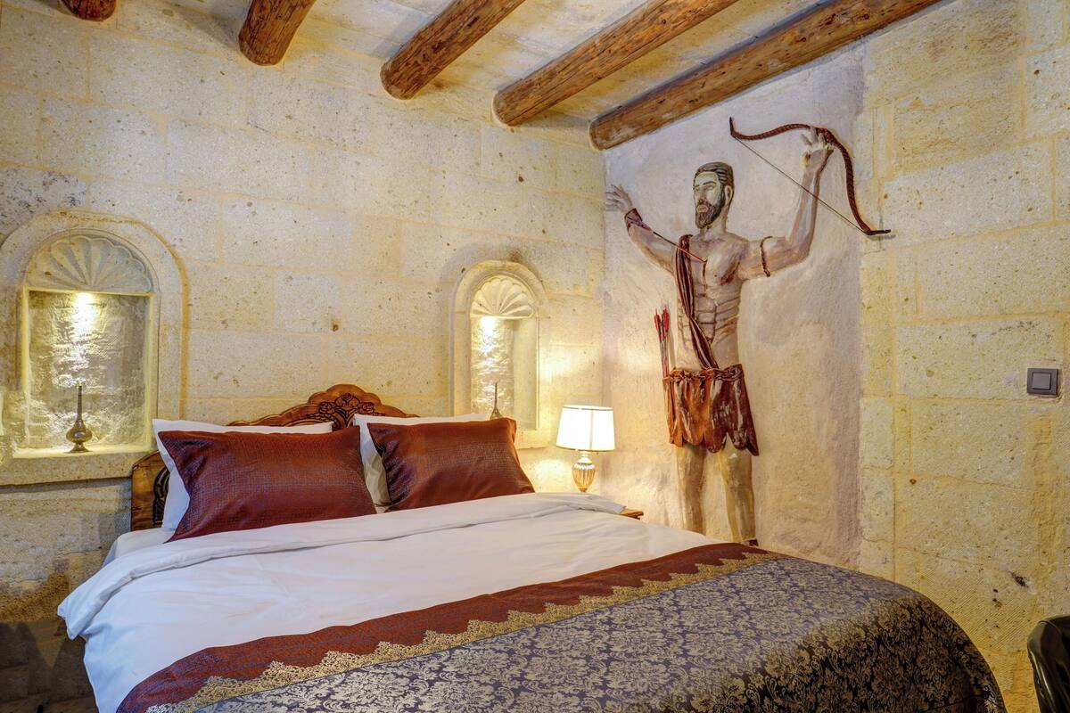 Ein Schlafzimmer mit einem Bett, einem Wandgemälde einer Person, einem Fenster und einer Lampe.
