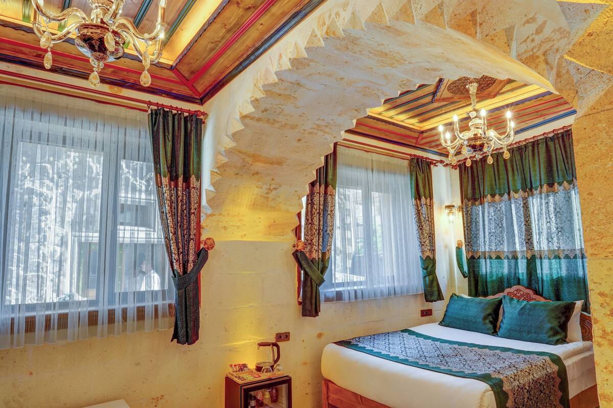 Ein Zimmer mit einem Bett, einer Chandelier und Vorhängen.