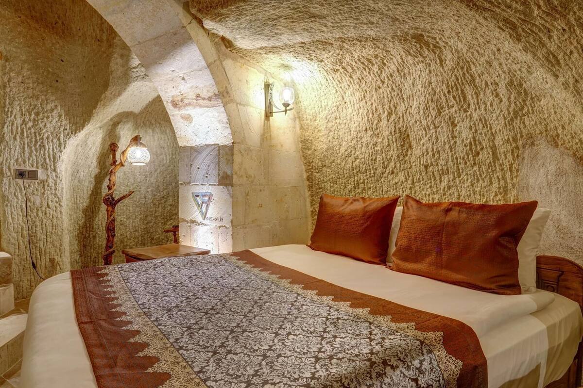 Ein gemütliches, rustikales Schlafzimmer mit einer Steinwand, einem hölzernen Bett und einem gemusterten Teppich.