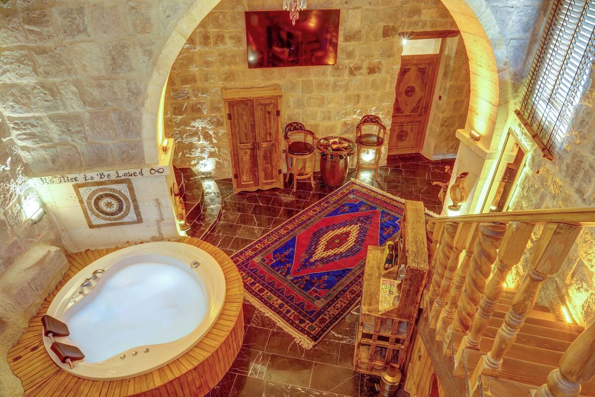 Ein luxuriöses Badezimmer mit einer großen Badewanne, Holzmöbeln und einem dekorativen Teppich.