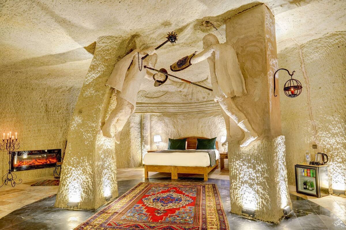 Ein Zimmer mit einem Bett, einem Kamin, einem Teppich und einem kleinen Kühlschrank.