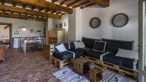 A rustic interior with a wooden ceiling, a dining area, and a sofa set on pallets. - Le Fornaci - Apartment with pool (Latereto)