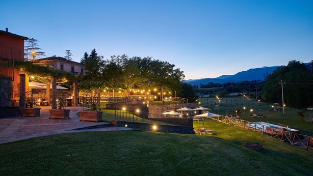 An outdoor patio area with tables and chairs, a pool, and a view of mountains in the background. - Le Fornaci - Apartment with pool (Latereto)