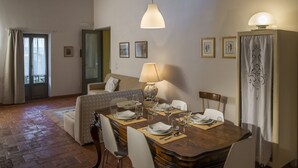 Een eetruimte met een houten tafel voor vier personen, een bank en een lamp.