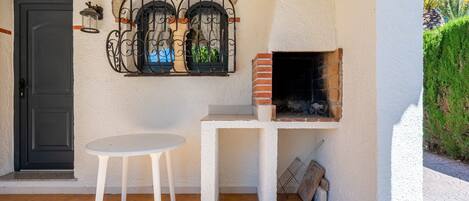 A patio area with a white table, a black door, and a brick oven.