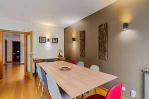 Ein Essbereich mit Holztisch, Stühlen und wandmontierten Leuchten.