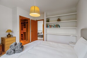 Ein Schlafzimmer mit einem Bett, einem Nachttisch, einer Lampe, einem Kleiderschrank und einem Bücherregal.