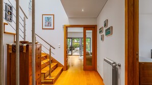 A hallway with wooden flooring, a staircase, and a door leading to a balcony. - Casa das Fontes – House of Wells with Mountain View, Private Garden and Wi-Fi (Parede)