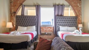 Ein Hotelzimmer mit zwei Betten, einer Ziegelwand und Blick durch ein Fenster.