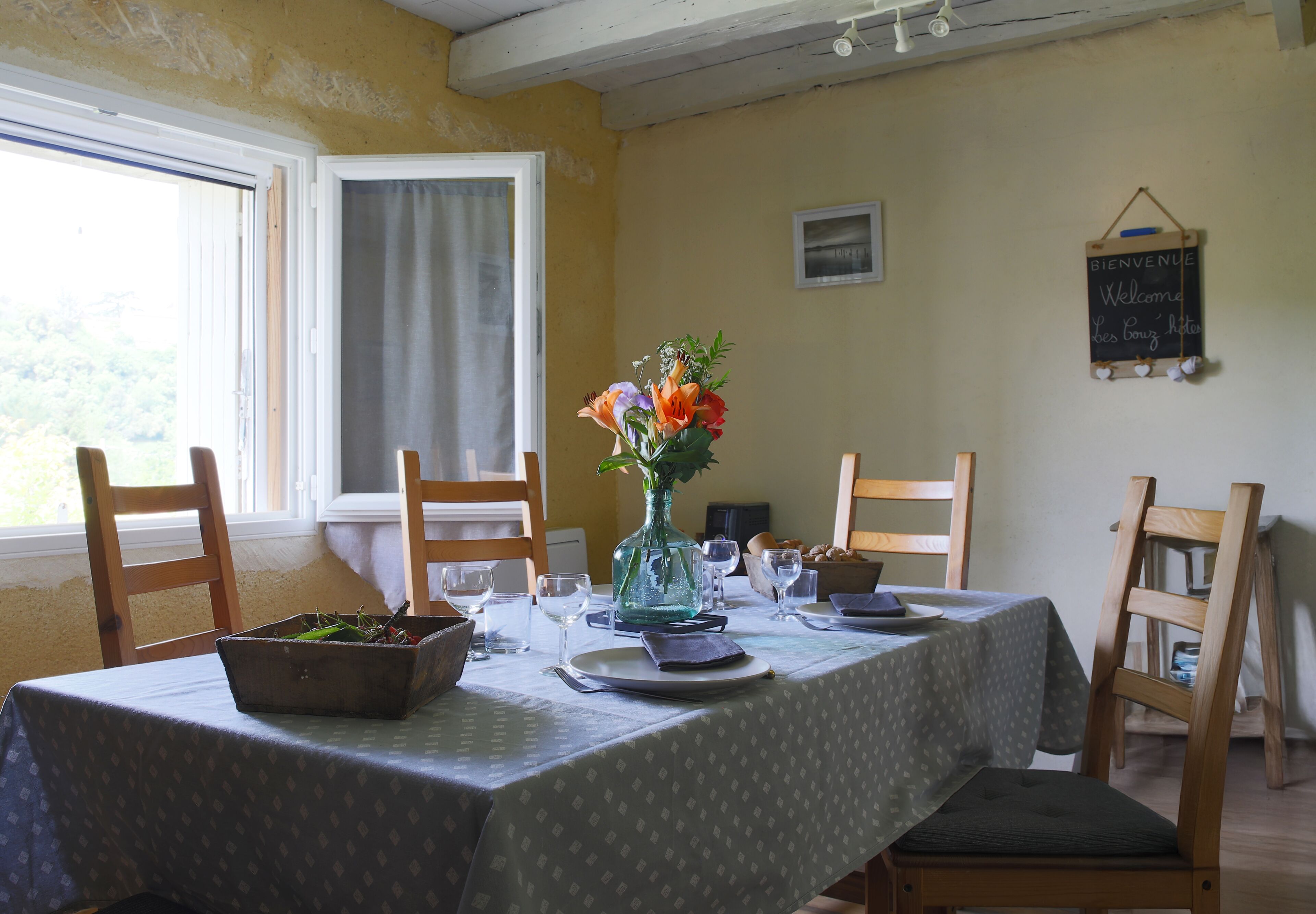Una mesa de comedor lista con un jarrón de flores, platos y cubiertos.