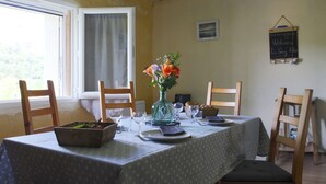 Une table à manger dressée avec un vase de fleurs, des assiettes et des couverts.