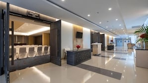 Et hotel med lobby, reception, siddeområde og et synligt mødelokale.