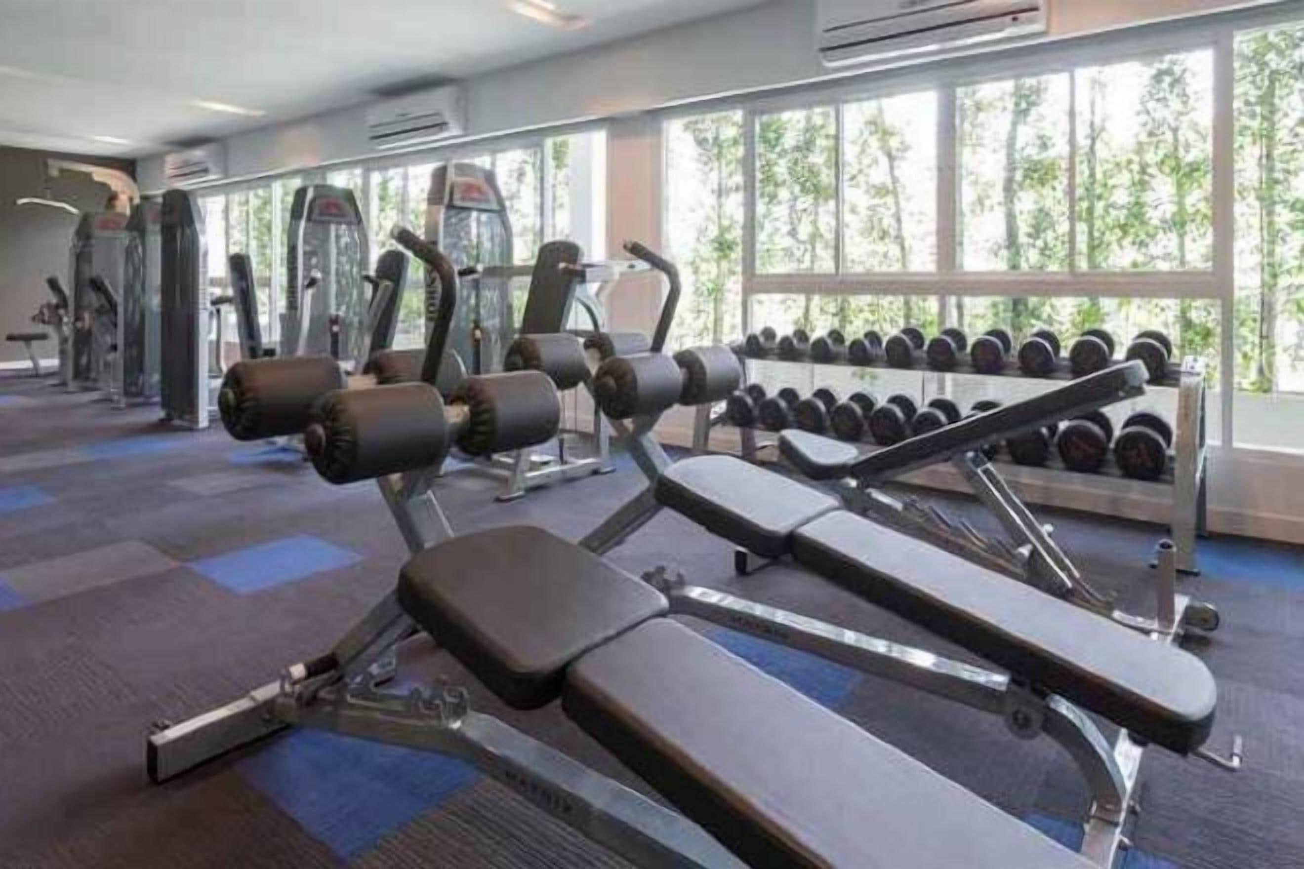 A gym with weight machines, dumbbells, and exercise mats.