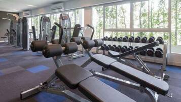 A gym with weight machines, dumbbells, and exercise mats.